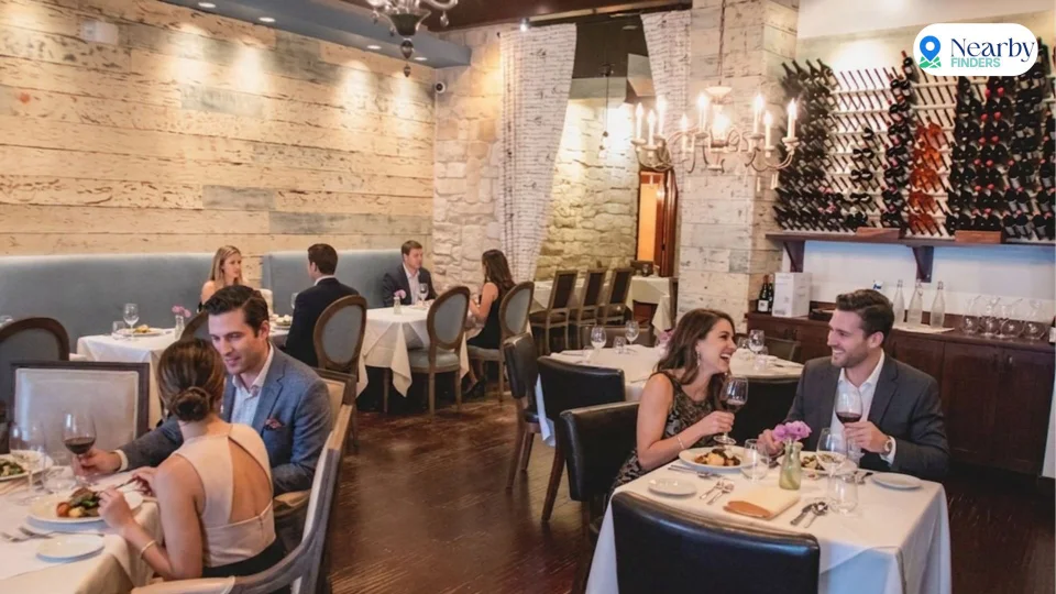 Romantic restaurants for couples in Houston: Couples dining at intimate white tablecloth tables under warm chandelier lighting inside Étoile Cuisine et Bar